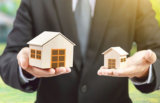 Two dummy houses of different size in someone’s both palm